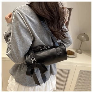 Detailed back view of black cylinder shoulder bag with oversized bow and silver hardware