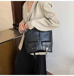Detail of large black PU leather tote bag with dual front pockets and silver metal buckles