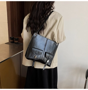 Rear view of a black faux leather backpack with double front pockets and adjustable straps