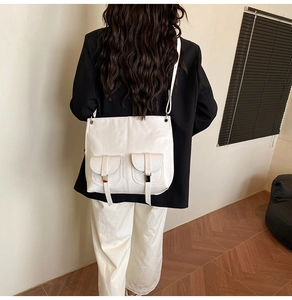 Detailed back view of model wearing a minimalist white crossbody bag with dual pockets