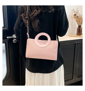 Détail du sac à main rose clair à monogramme avec poignée ronde et surface texturée