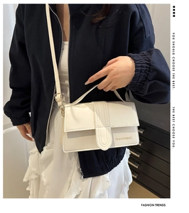 Moderna borsa bianca con patta e tracolla indossata su una giacca blu scuro