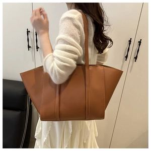 Detailed macro view of the large brown PU leather tote bag showing fine texture and logo