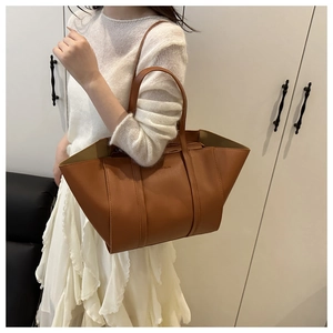 Detail view of large brown faux leather tote bag with embossed fashion text and side wings