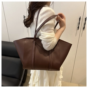 Detail of dark brown tote bag showing matte PU leather texture and wide trapezoid structure
