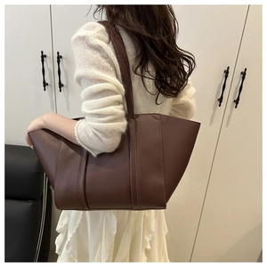 Detail of large dark brown tote bag on model showing size and minimalist style