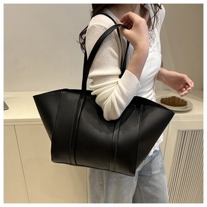 Close-up of a large black matte leather tote bag worn on shoulder for daily commute