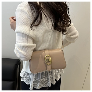 Detail of beige glossy leather bag featuring a vintage gold CD-shaped metal buckle on the flap