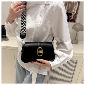 Close-up of black crossbody bag with gold buckle and black-white geometric wide strap