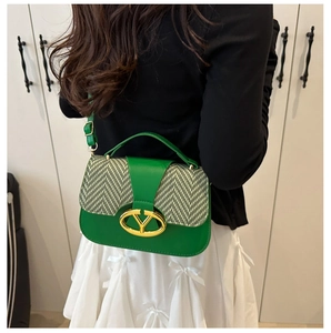 Detalle del bolso bandolera de cuero verde y espiguilla con hebilla metálica en V dorada
