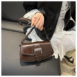Detail of vintage dark brown faux leather shoulder bag with silver buckle and glossy finish