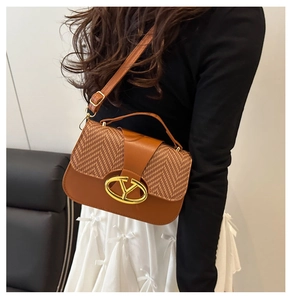Detalle de bolso de silla marrón con tejido de espiga y logo en V de metal dorado