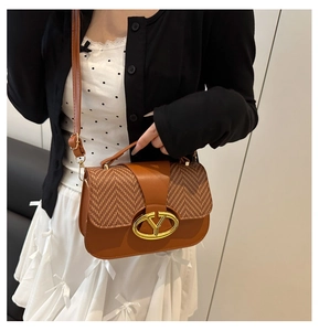 Detalle del bolso de montura caramelo con textura de espiga y hebilla dorada