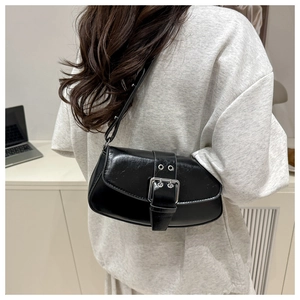 Detail of minimalist black glossy saddle bag with silver buckle on a shoulder
