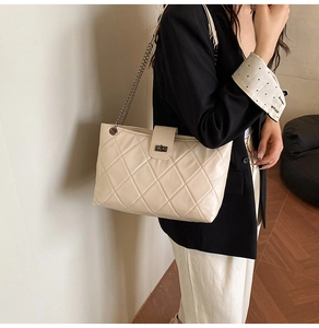 Detailed close-up of beige quilted texture and gold chain strap on women's shoulder bag