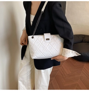 On-body shot of a white quilted tote bag featuring a chain strap and flap twist lock