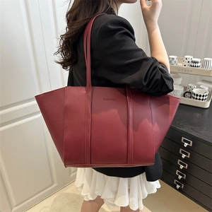Large capacity dark red leather tote bag with FASHION logo shown on shoulder in chic interior