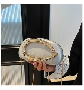 Detail der silbernen Clutch mit großem goldenem C-Verschluss und edler Metallkette