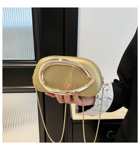 Nahaufnahme der champagnergoldenen Abendtasche mit Metallring und Kettenriemen