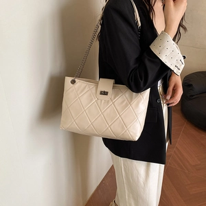 Quilted cream tote bag with gold chain strap shown on model for a stylish casual look