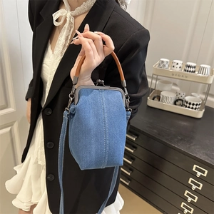 Retro blue denim crossbody bag with metal clasp and caramel handle worn by a model