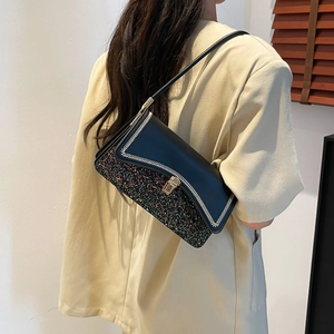 Chic black leather shoulder bag with glitter trim and woven details worn by a model