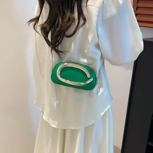 Elegante grüne ovale Abendtasche mit goldener Ring-Schnalle und Kette am Modell getragen