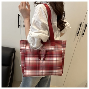 Dettaglio della borsa tote a quadri rossi con spalline larghe e cerniere decorative