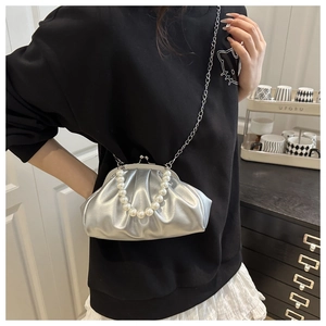 Close-up of metallic silver pleated cloud bag with pearl handle and metal chain strap