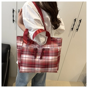 Detail of red plaid tote bag with nylon straps shown from a side view on a model