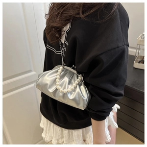 Detail of silver pleated cloud bag featuring pearl handle and fine metal chain strap