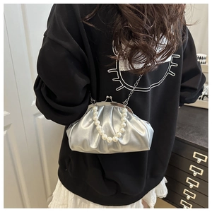 Detail of silver pleated handbag with pearl handle and metal chain in daily use