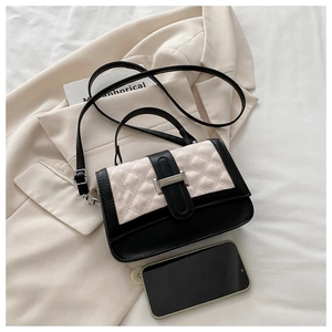 Detail of quilted leather flap with black and white contrast on stylish crossbody handbag