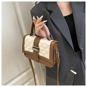 Detail of quilted leather crossbody bag in brown and cream with metal clasp on model