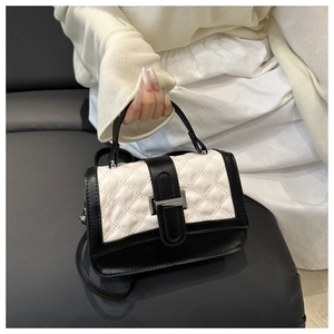 Detail of quilted leather handbag with contrast black and white design and metal clasp