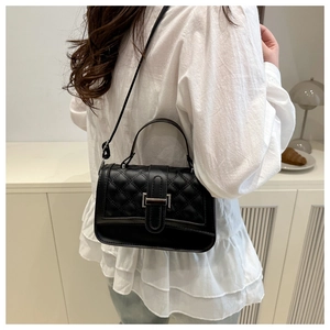 Detail of black quilted crossbody bag with silver buckle and adjustable shoulder strap