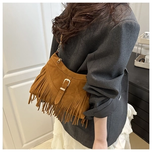 Close-up of brown suede fringe tote bag with metal chain strap and decorative buckle