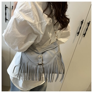 Detailed view of light gray faux suede crossbody bag featuring long stylish tassels