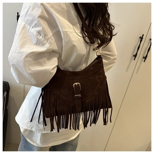 Detail of dark brown suede crossbody bag with vintage tassels and metal chain strap
