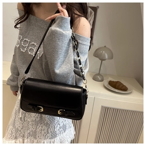 Detail of a vintage black square shoulder bag with gold buckle straps and chain strap