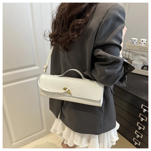 Close-up of white crocodile pattern bag with golden swivel lock and adjustable strap