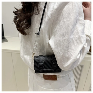 Detail of black crossbody bag with carbon fiber texture and modern acrylic chain strap