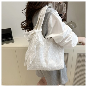 Detailed shot of white floral lace embroidery tote bag with a large bow decoration