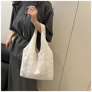 Detail shot of white heavy lace embroidery on a canvas tote bag with floral patterns