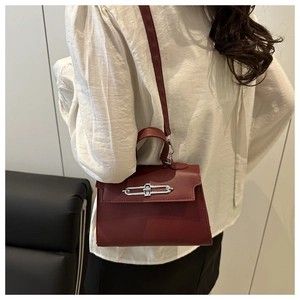 Closer view of burgundy trapezoid bag with silver buckle worn as a crossbody purse