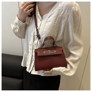 Deep red leather trapezoid handbag with silver metal lock and adjustable shoulder strap