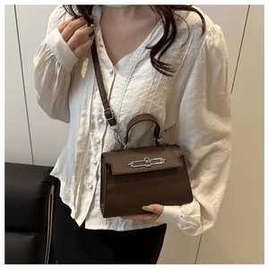 Detail of dark brown leather crossbody bag featuring silver metal twist lock and top handle