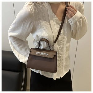 Deep brown trapezoid handbag with silver buckle worn by a model in a white shirt