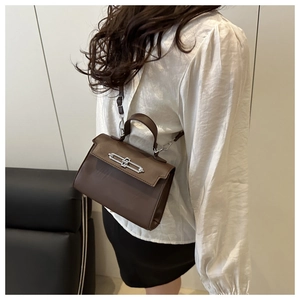 Close-up of dark brown leather Kelly bag with silver metal lock worn by a model