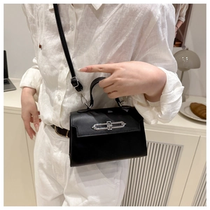 Detail of a structured black leather square bag with a metallic silver turn-lock closure